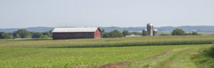 Farm scene with red barn and silo in distance
